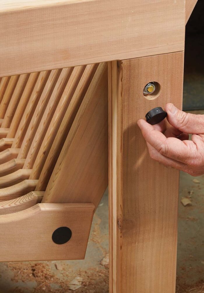 Asa places a plastic cap over the end of exposed hardware, the last step of assembling the chair. 