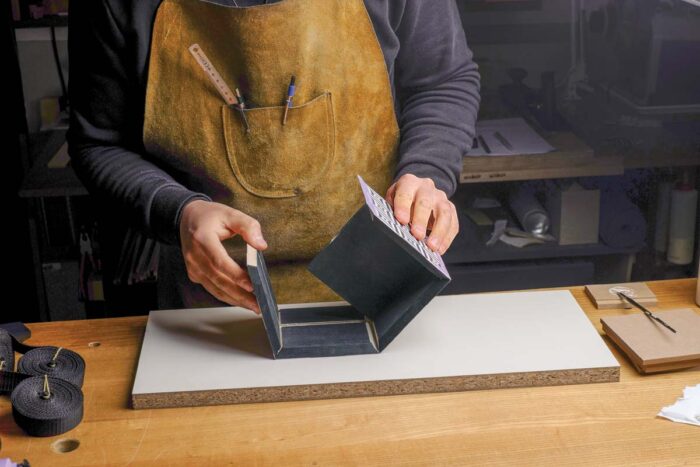 Vasko folds the box closed, held together with tape and glue in the miter seams.