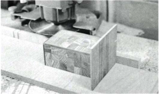 The same box set in front of a radial arm saw thats been oriented horizontally. A thin piece of plywood is set as a backer behind the box.